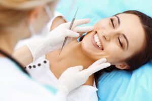 young female patient visiting dentist office beautiful woman with healthy straight white teeth sitting dental chair with open mouth during oral checkup while doctor working teeth dental clinic
